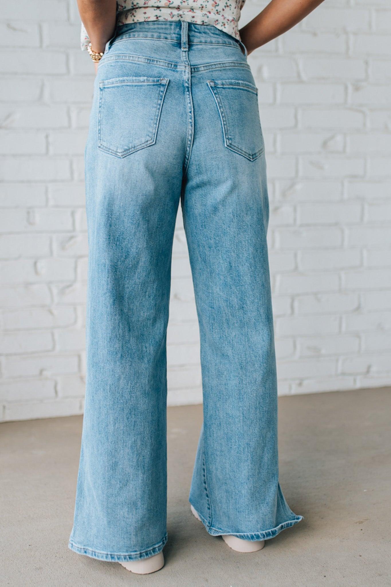BLONDE WOMAN WEARING DRAWSTRING WAIST DETAIL STRETCH SIDE SLIT WIDE LEG JEAN IN MEDIUM BLUE.
