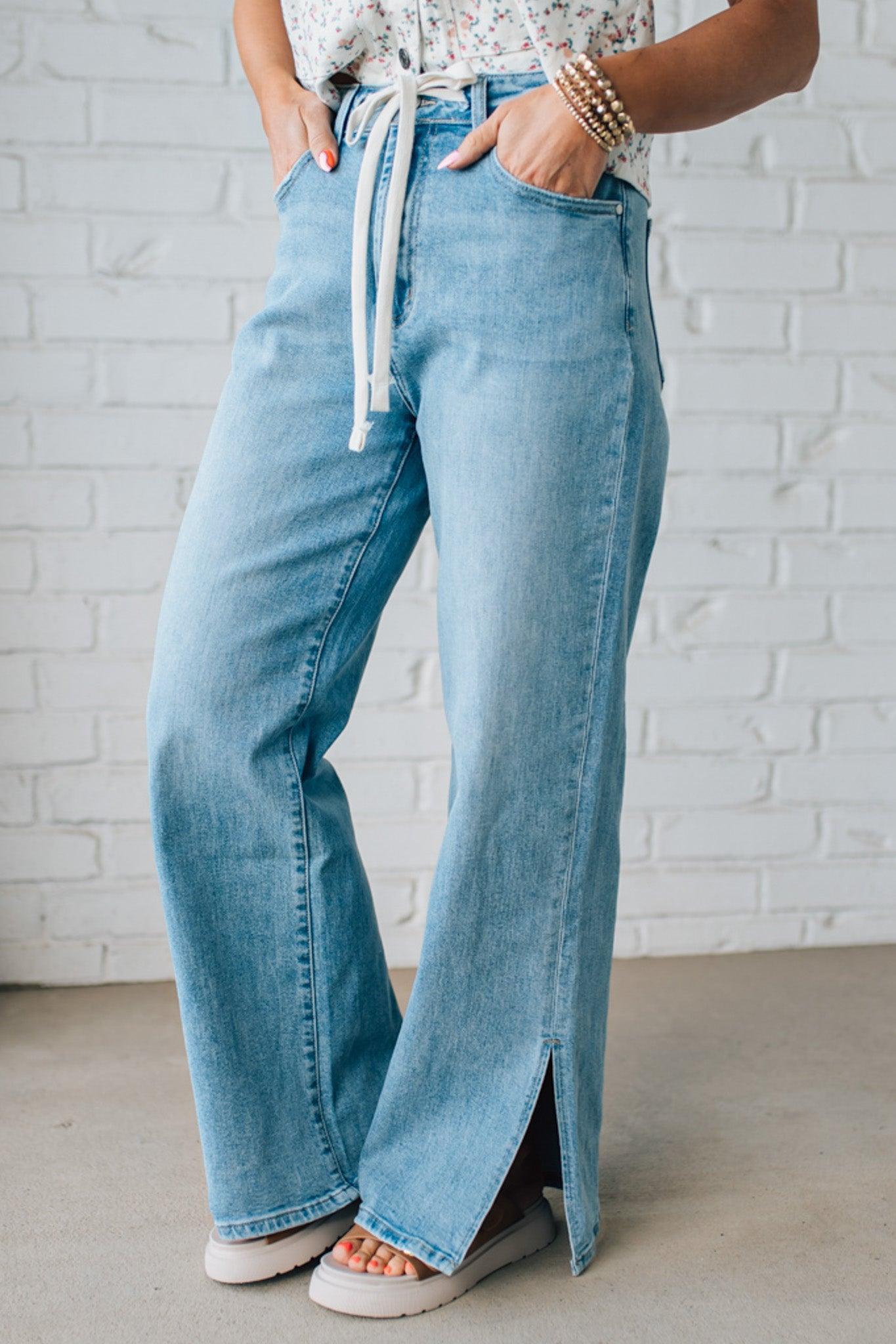 BLONDE WOMAN WEARING DRAWSTRING WAIST DETAIL STRETCH SIDE SLIT WIDE LEG JEAN IN MEDIUM BLUE.