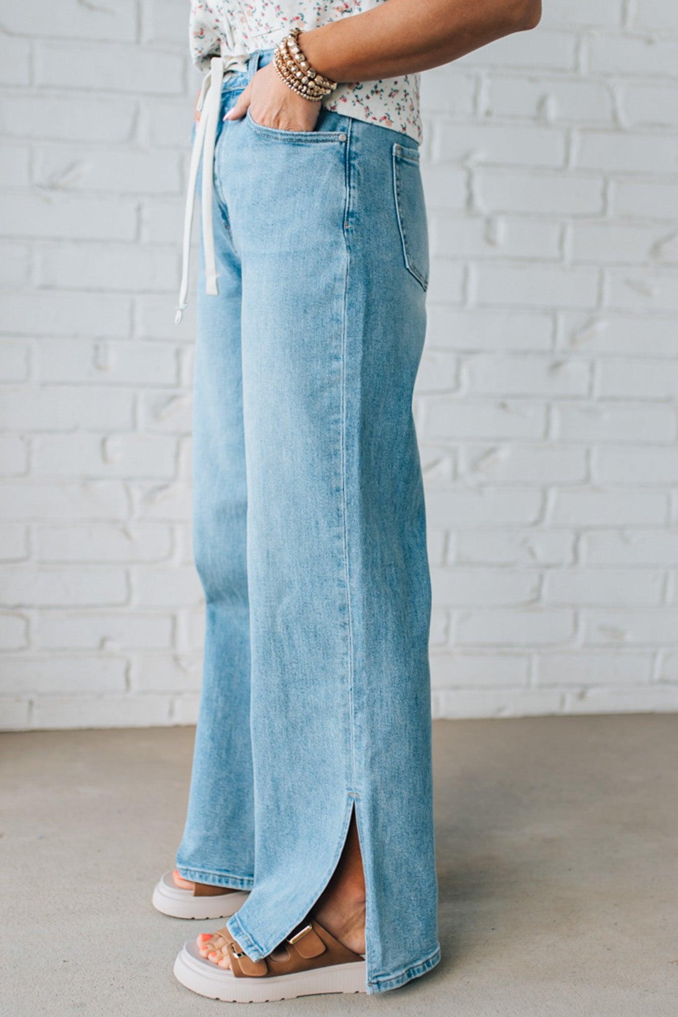 BLONDE WOMAN WEARING DRAWSTRING WAIST DETAIL STRETCH SIDE SLIT WIDE LEG JEAN IN MEDIUM BLUE.