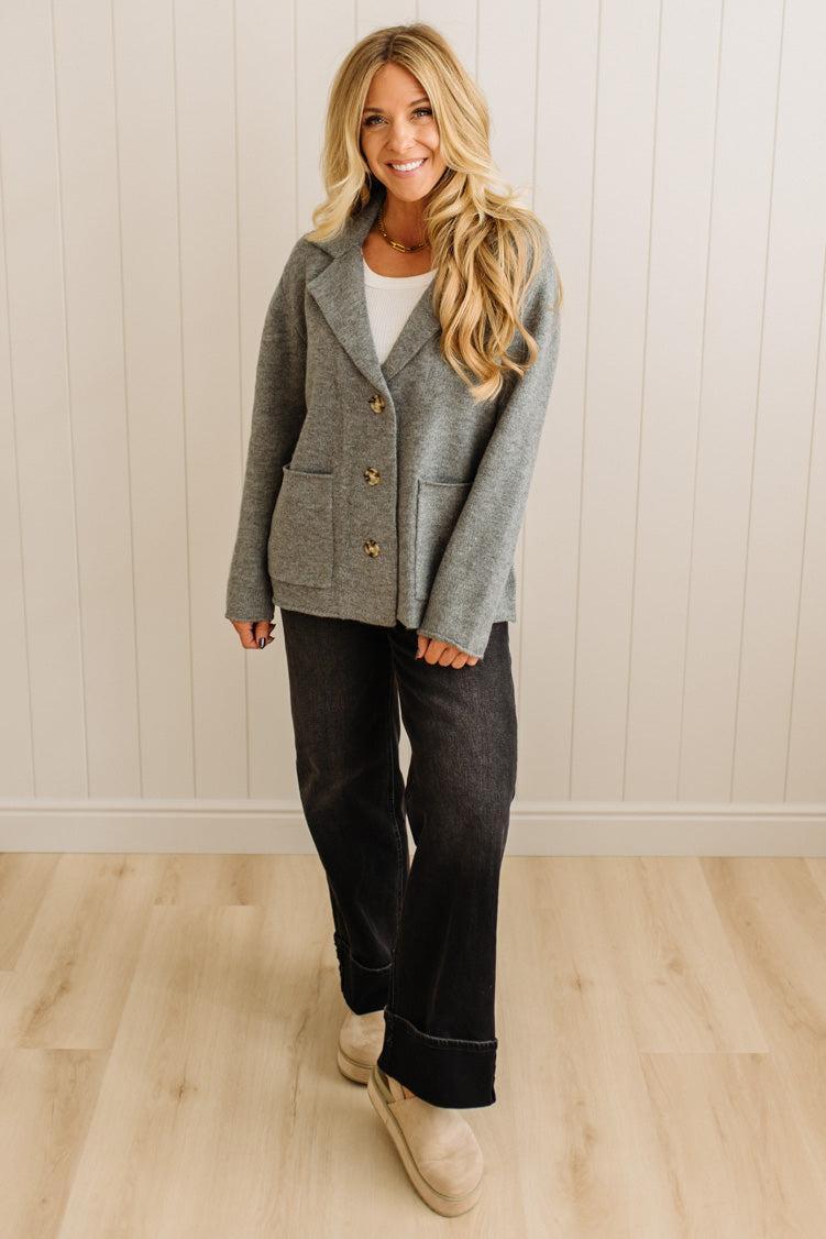 Blonde woman wearing a grey classic notched lapel sweater cardigan with tailored lines and patch pockets.