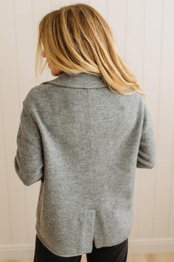 Blonde woman wearing a grey classic notched lapel sweater cardigan with tailored lines and patch pockets.