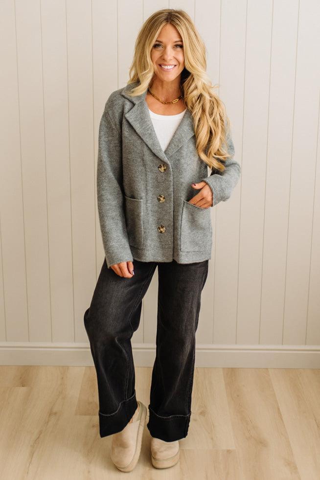 Blonde woman wearing a grey classic notched lapel sweater cardigan with tailored lines and patch pockets.
