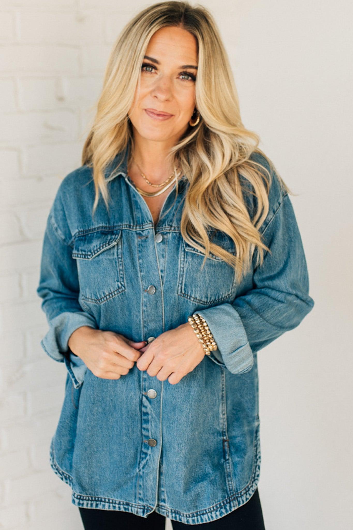 A woman wearing a light blue denim shacket with long sleeves, featuring a round hem and side pockets, buttoned at the front.