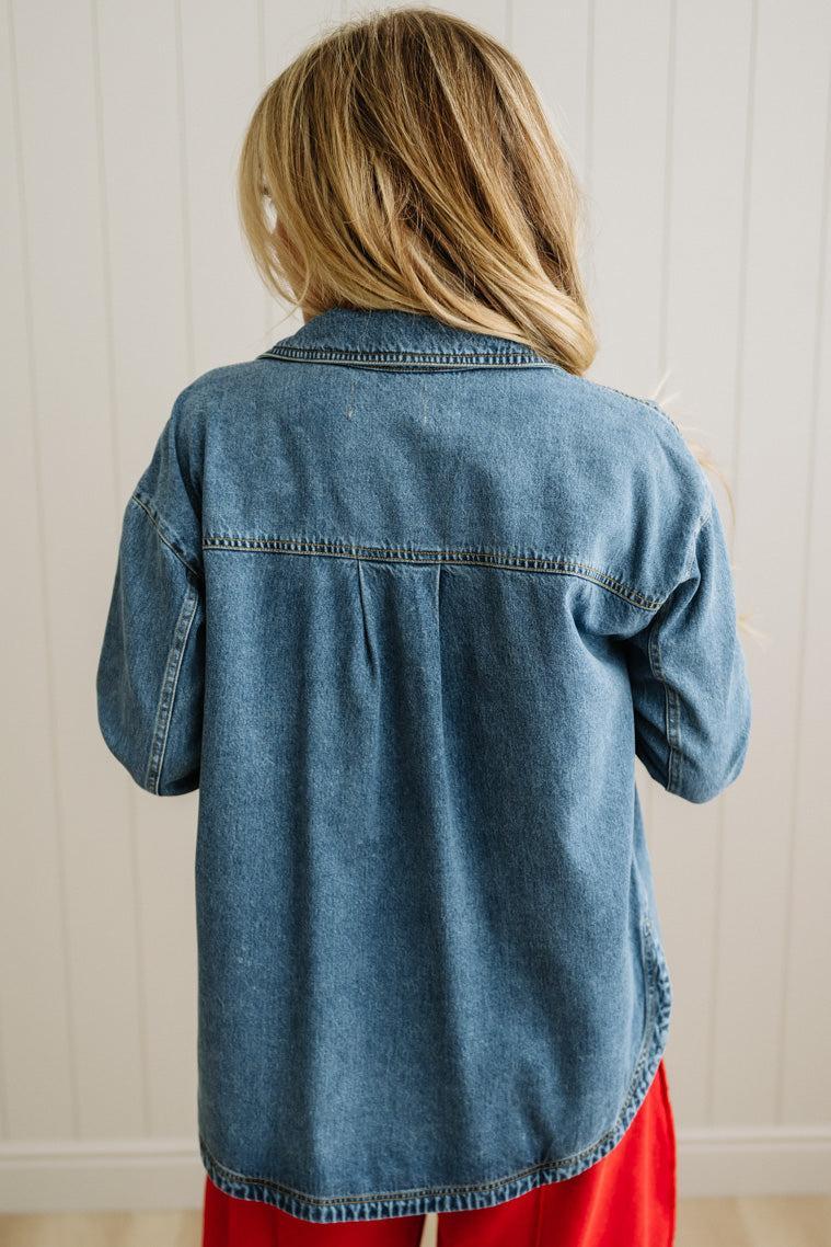 Person wearing a blue denim shirt with a neutral background