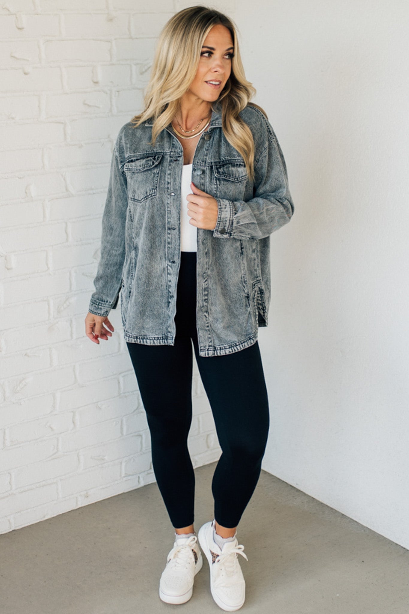 A woman wearing a light blue denim shacket with long sleeves, featuring a round hem and side pockets, buttoned at the front.