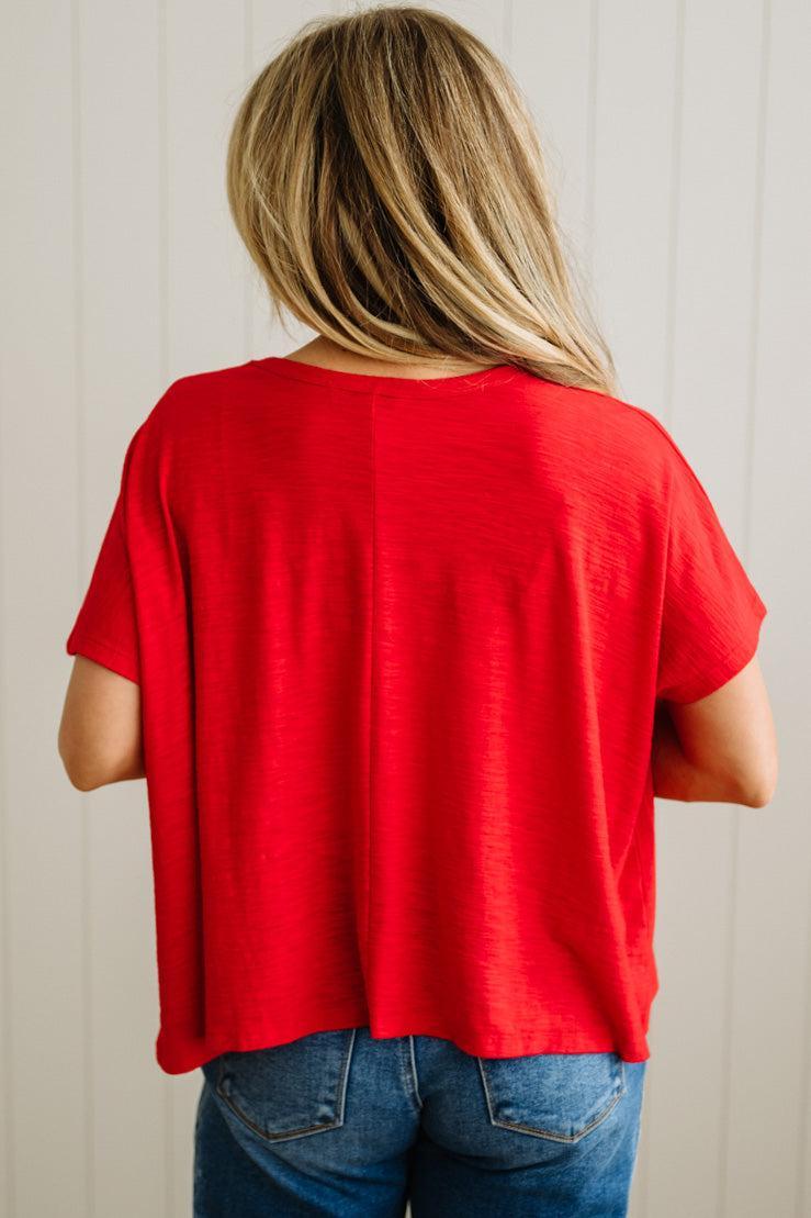 Person wearing a red shirt and blue jeans against a neutral background