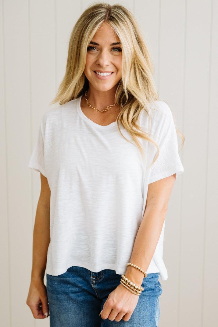 Woman wearing a white t-shirt and blue jeans with a neutral background