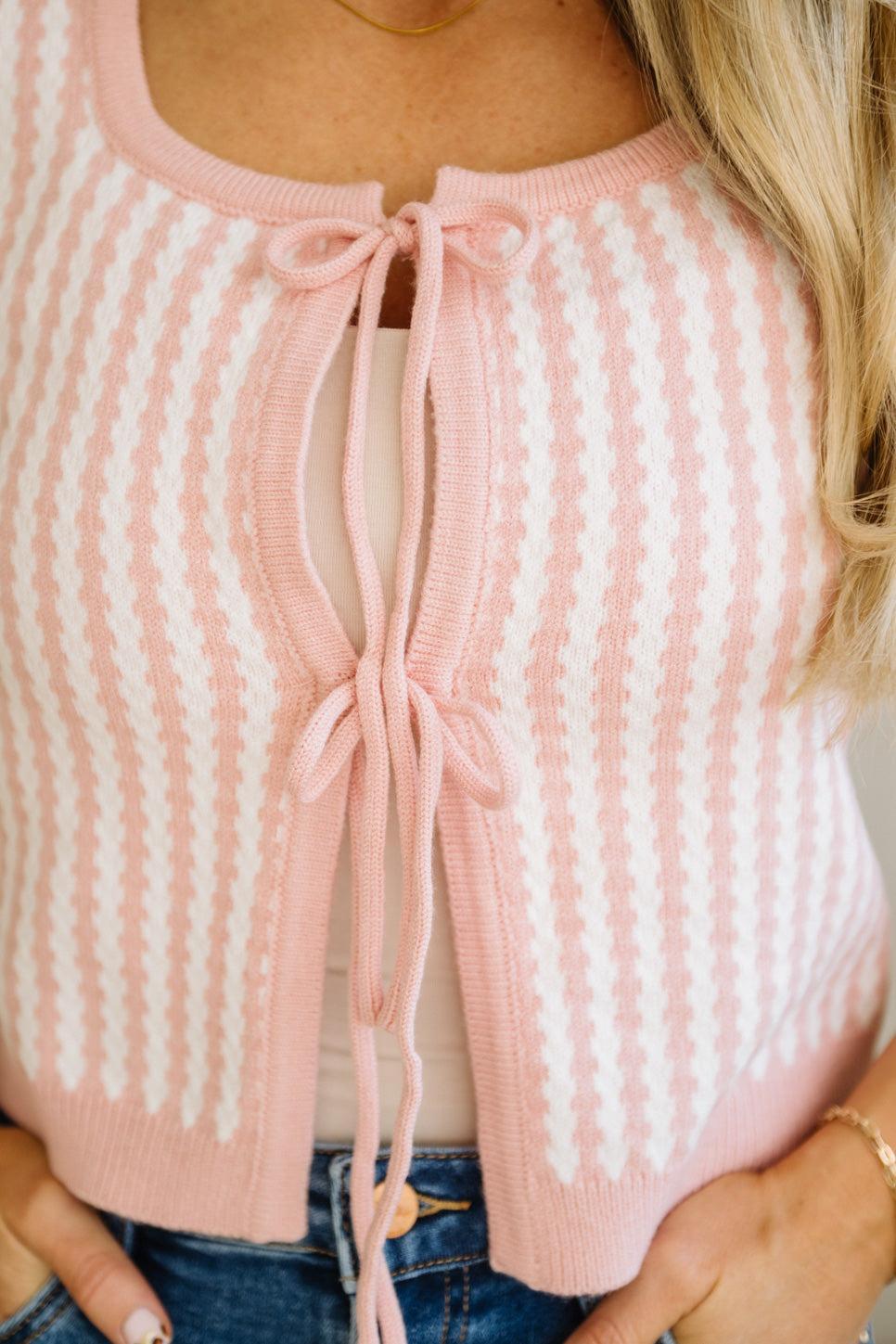 Pink and white striped sweater with a tie detail on a person.