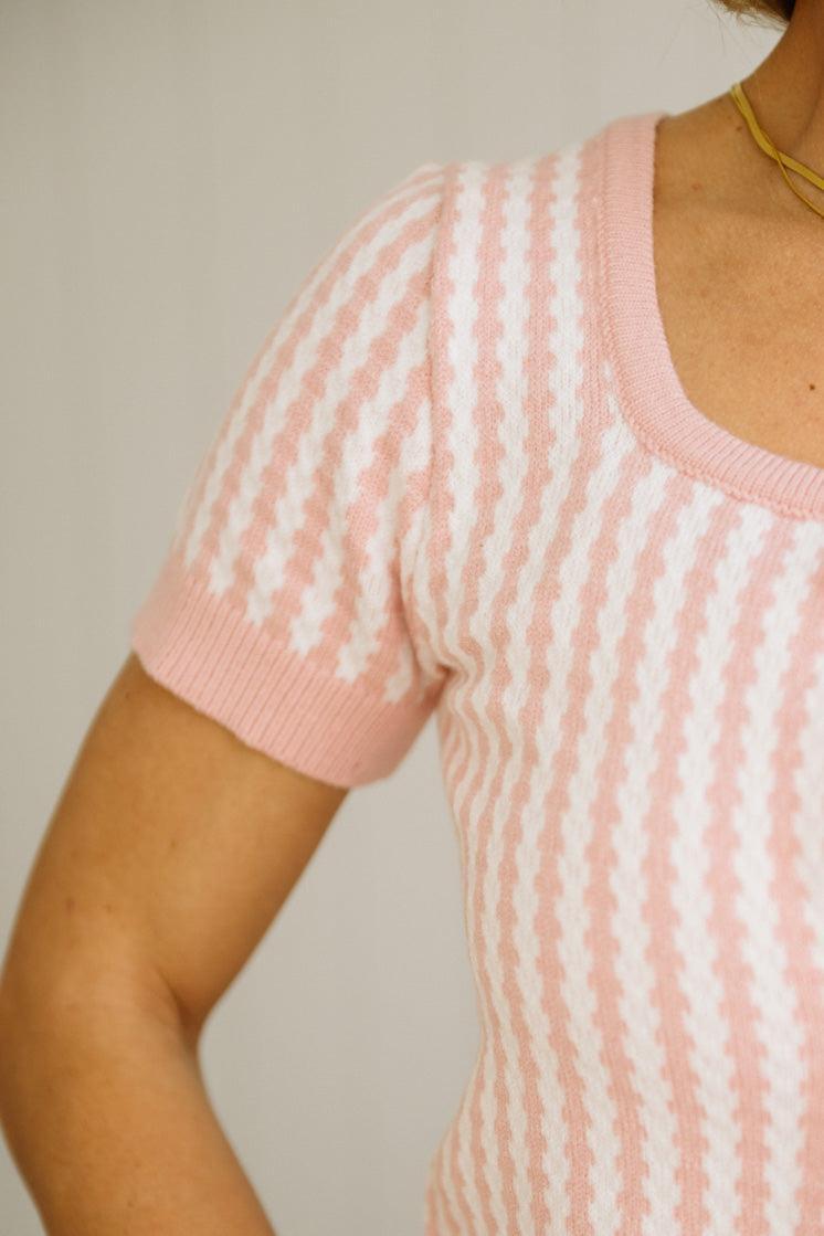 Person wearing a pink and white striped sweater against a neutral background