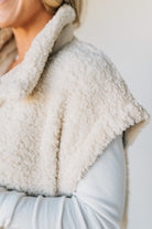 Close-up of a person wearing a light-colored sherpa-lined jacket with a blurred background