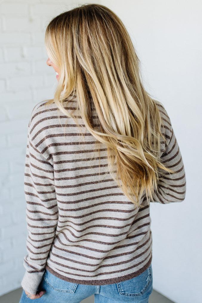 Person wearing a striped sweater with a plain background