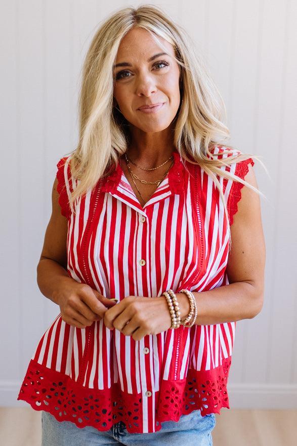 Woman wearing a red and white striped blouse with lace details on a plain background