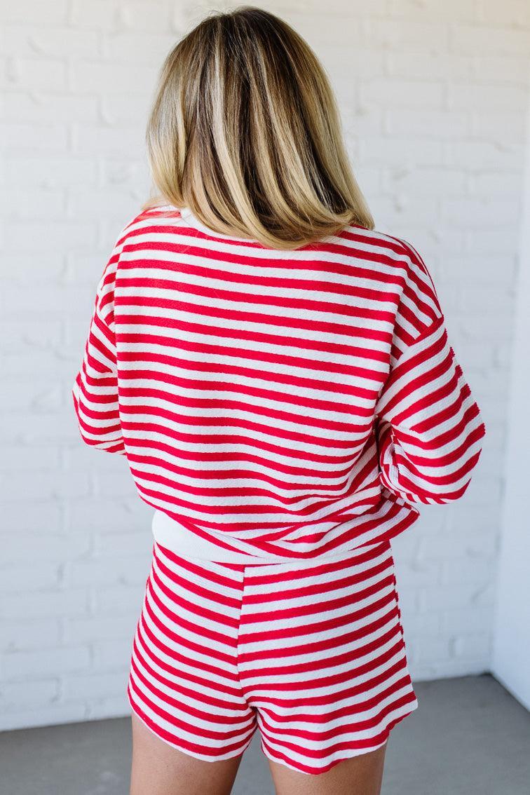 Person wearing a red and white striped outfit against a white wall.