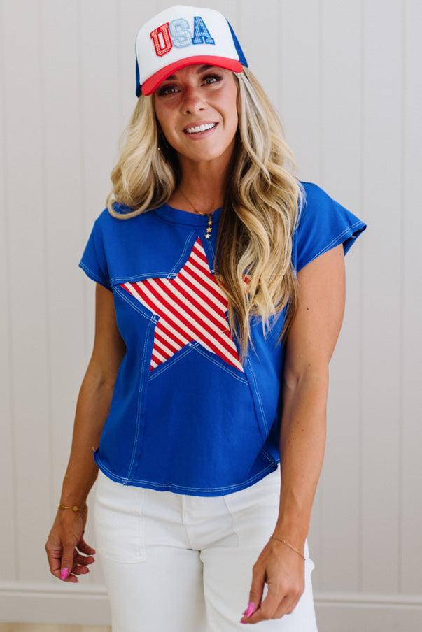 Woman wearing a blue top with an American flag design and a 'USA' cap.