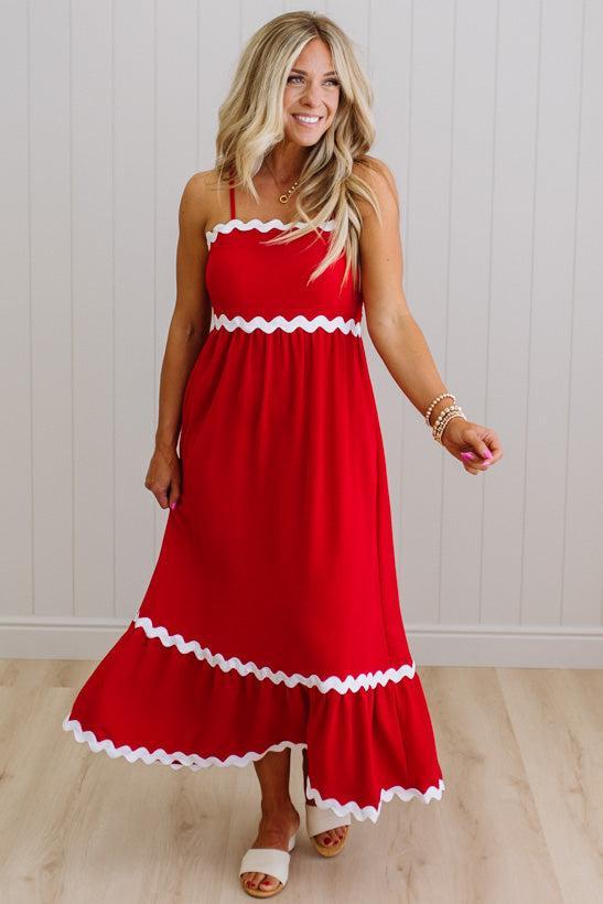 Woman wearing a red dress with white trim on a light wooden floor.