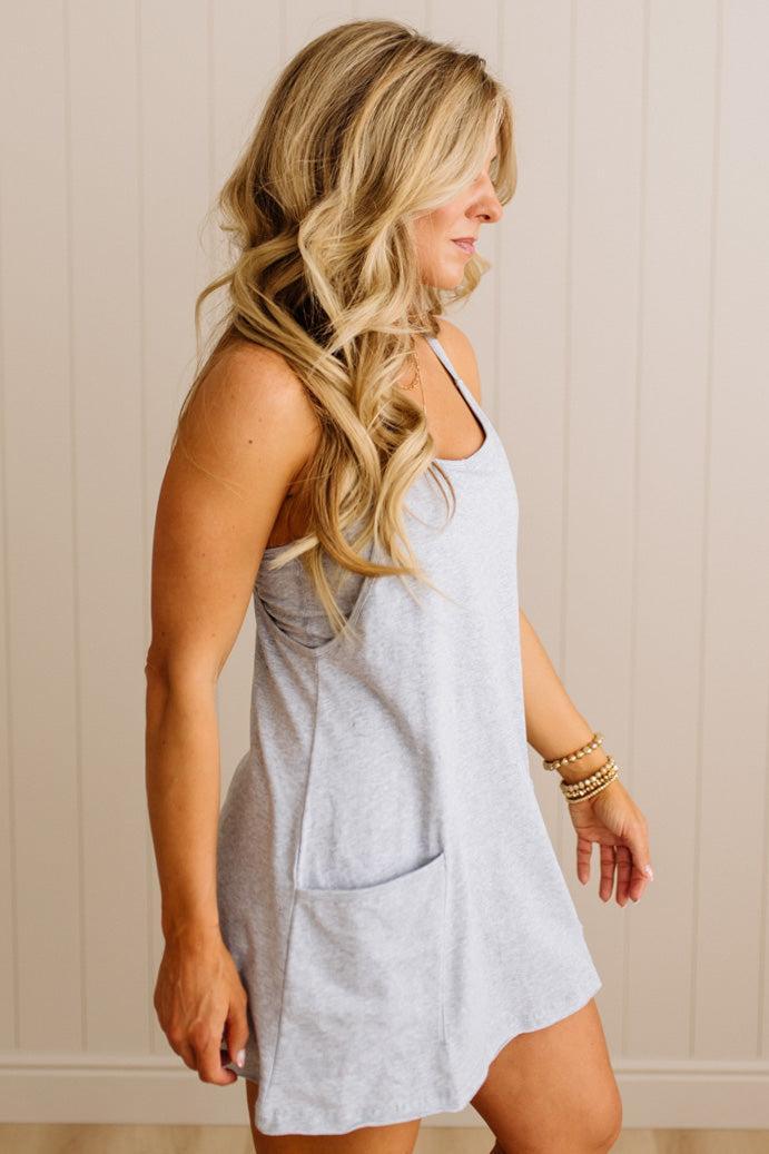 Woman wearing a light gray dress against a beige wall.