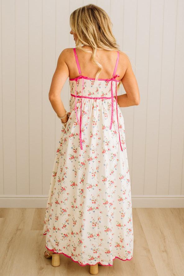 Woman wearing a floral dress with pink straps against a wooden panel background