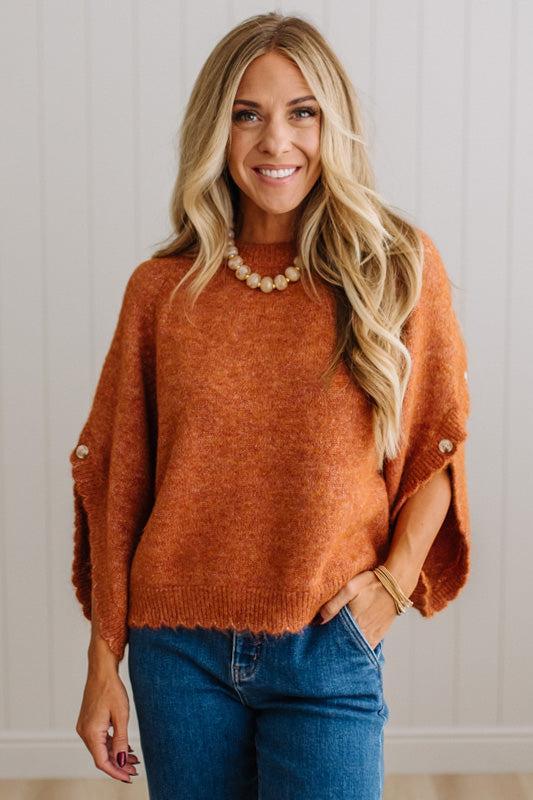 BLONDE WOMAN WEARING DARK JEANS IN A BRIGHTLY LIT STUDIO WITH A SOLID SWEATER FEATURING SCALLOP TRIM AND BUTTONS UP THE SLEEVE IN THE COLOR HEATHERED RUST.