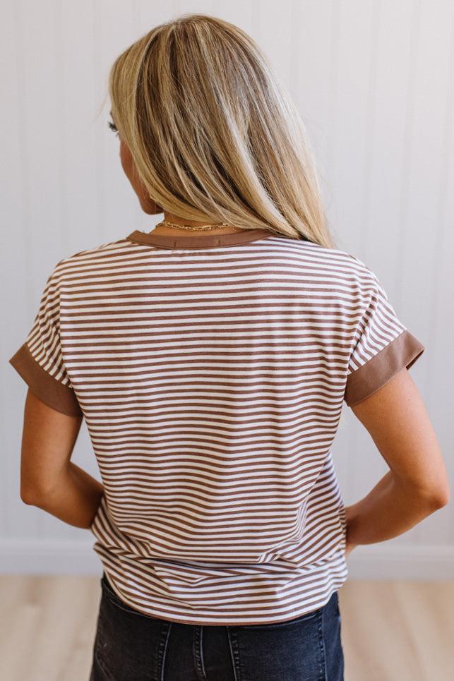 Woman wearing a striped shirt with brown and white colors against a plain background