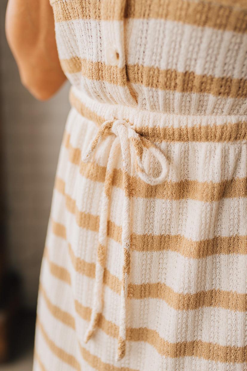 BLONDE WOMAN WEARING A TEXTURED BUTTON UP, STRETCH WAIS WAIST WITH DRAWSTRING, COLLARED MINI DRESS, WITH SIDE POCKETS.