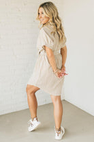 Blonde woman wearing a knee length striped shirt dress with button front and matching sash at waist.