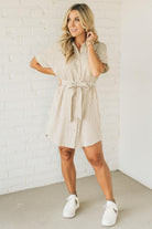 Blonde woman wearing a knee length striped shirt dress with button front and matching sash at waist.