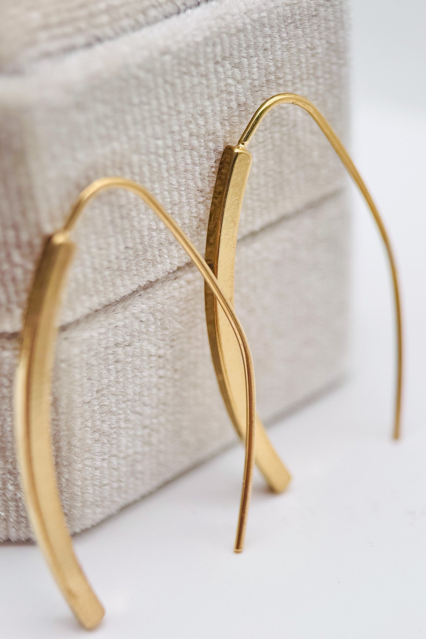 Gold hoop earrings on a textured fabric background