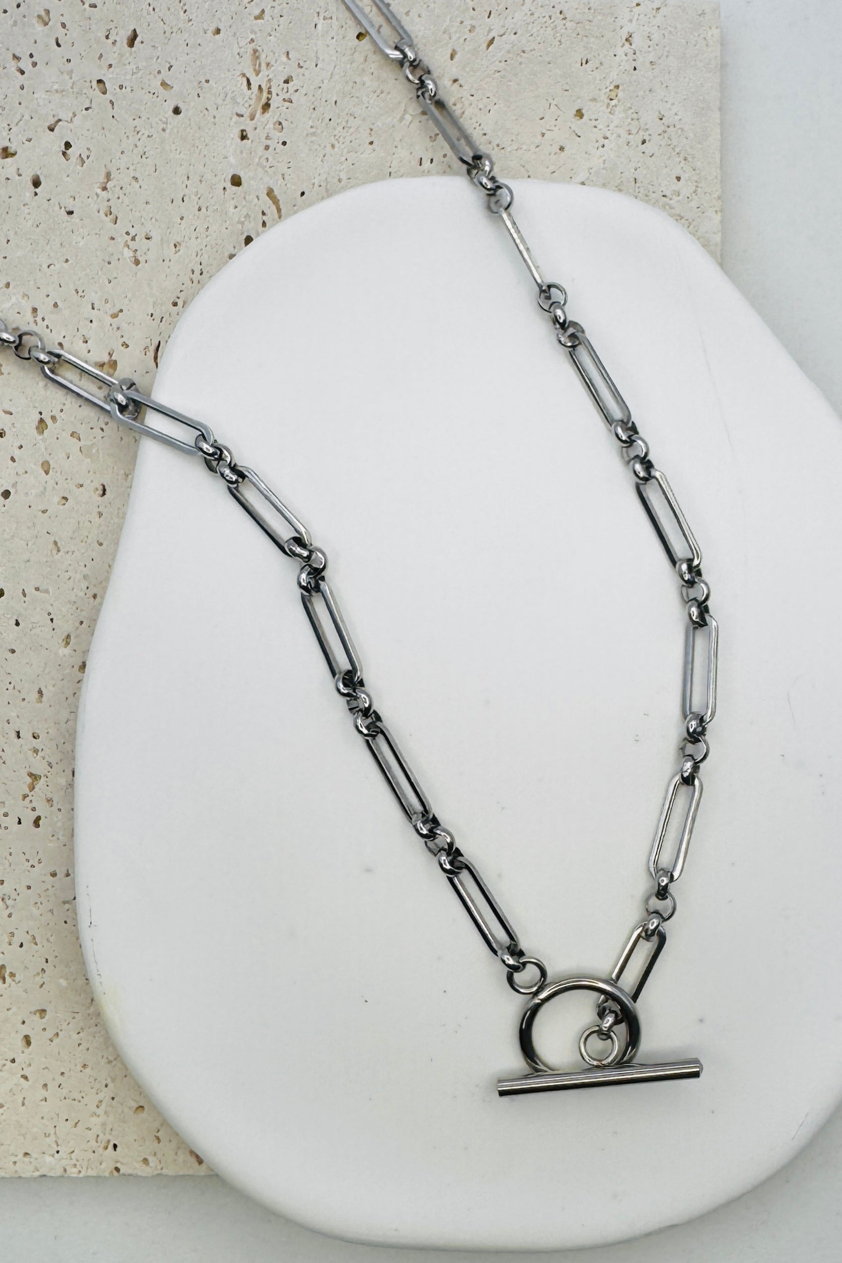 Silver chain necklace with a clasp on a white stone surface