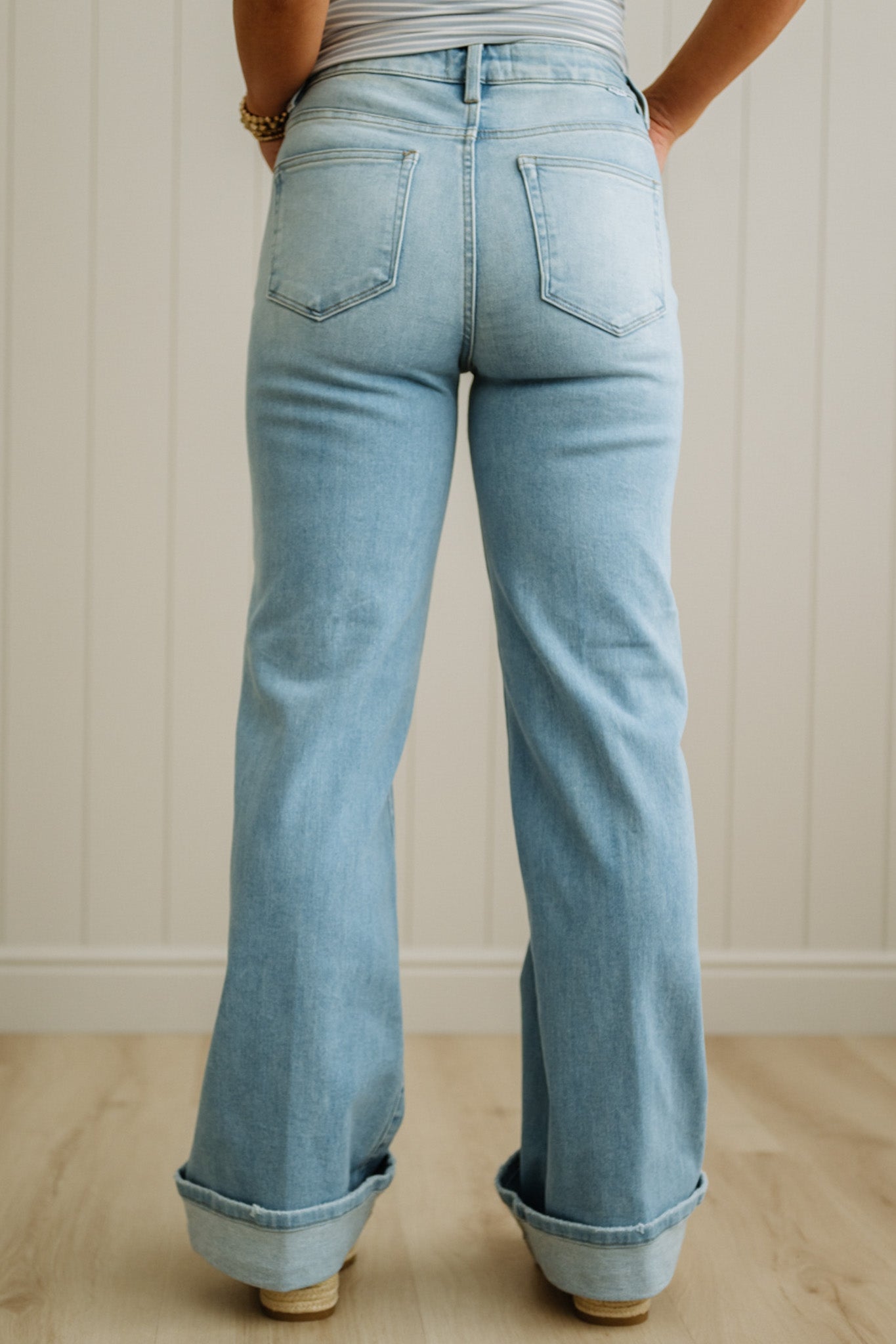 Light blue jeans worn by a person against a white paneled wall.
