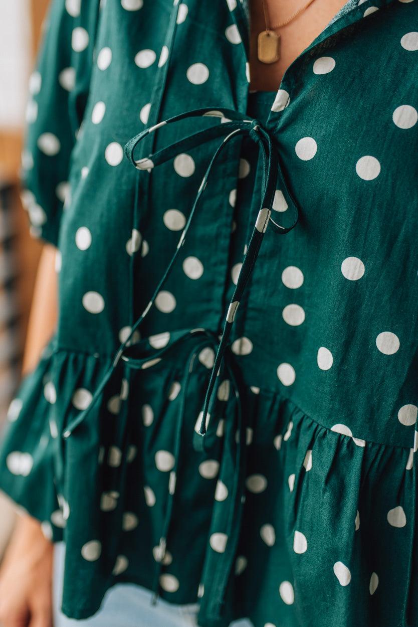 Green polka dot dress with a tie detail on a blurred background