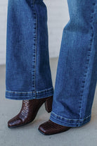 Blue jeans worn with brown crocodile-patterned high-heeled shoes on a neutral background