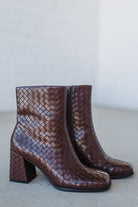 Pair of brown woven ankle boots on a light gray background