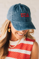 Blonde woman wearing a classic ball cap with USA embroidered at center front.