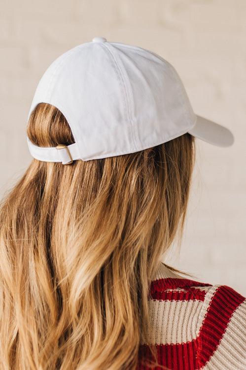 Blonde woman wearing a classic ball cap with USA embroidered at center front.