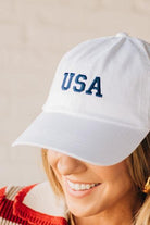 Blonde woman wearing a classic ball cap with USA embroidered at center front.