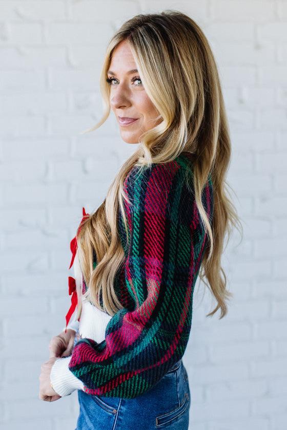 BLONDE WOMAN WEARING A VELVET BOW RIBBON EMBELLISHED CHRISTMAS CHECKER PLAID BUTTONED SWEATER CROP CARDIGAN