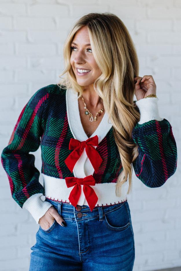 BLONDE WOMAN WEARING A VELVET BOW RIBBON EMBELLISHED CHRISTMAS CHECKER PLAID BUTTONED SWEATER CROP CARDIGAN