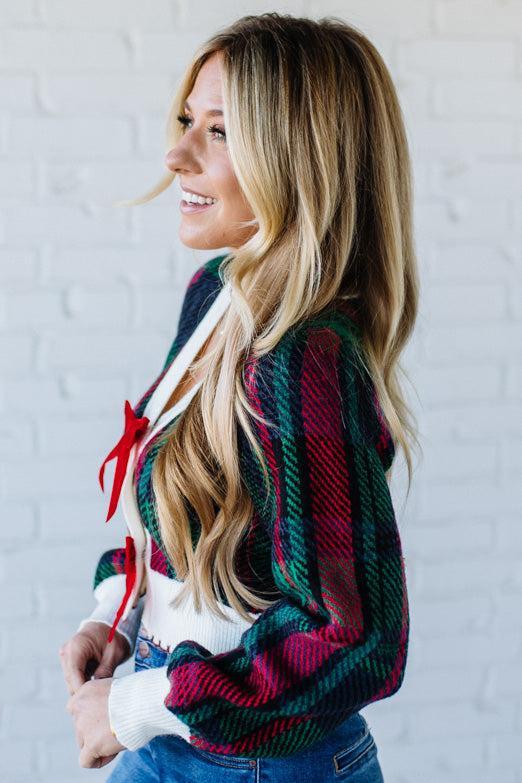 BLONDE WOMAN WEARING A VELVET BOW RIBBON EMBELLISHED CHRISTMAS CHECKER PLAID BUTTONED SWEATER CROP CARDIGAN
