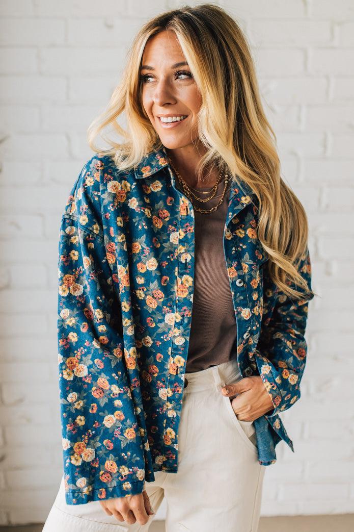 Woman wearing a blue floral jacket against a white brick wall