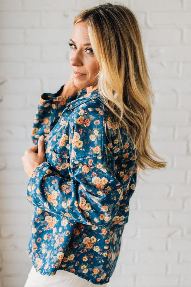 Woman wearing a blue floral jacket against a white brick wall