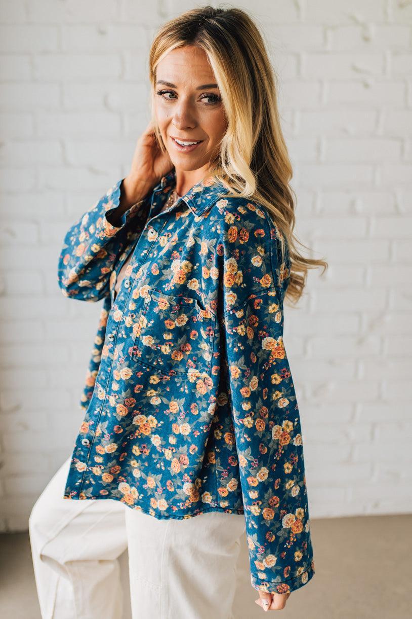 Woman wearing a blue floral blouse against a white brick wall