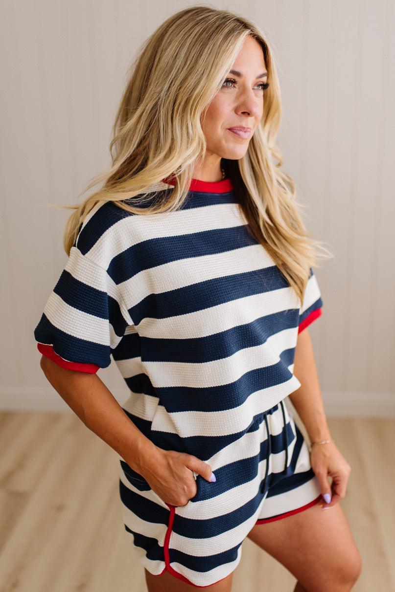 Woman wearing a navy and white striped set with red accents indoors.