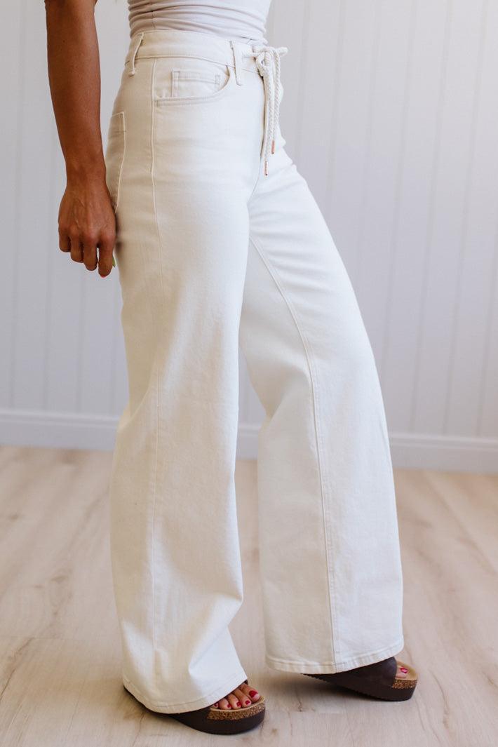 Person wearing white wide-leg jeans on a plain background