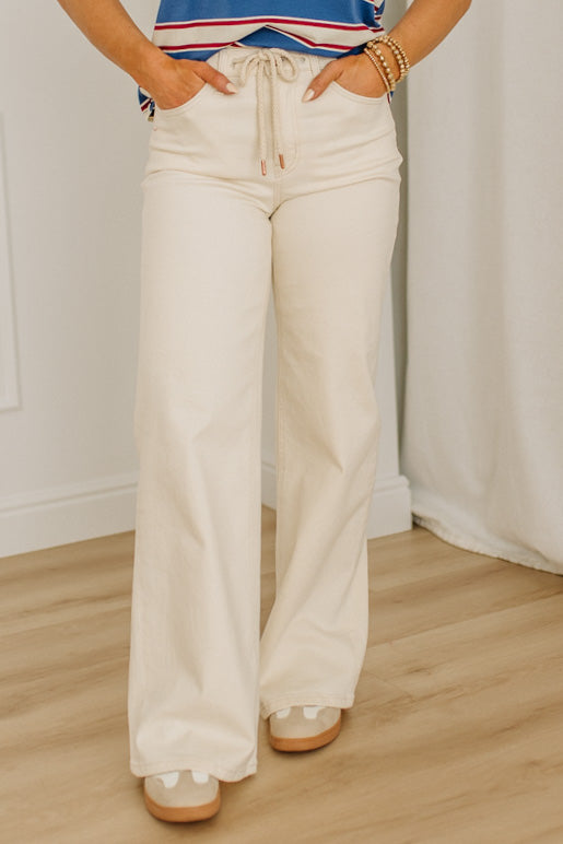 Person wearing white wide-leg pants with a plain background