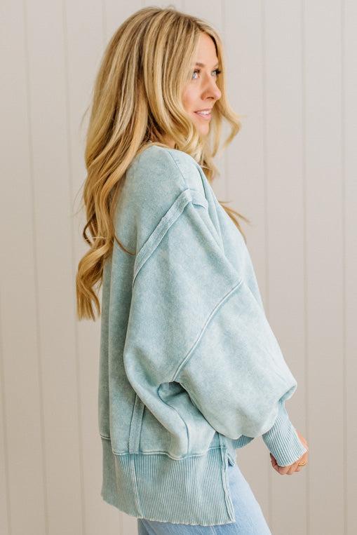 Woman wearing a light blue sweater against a beige wall