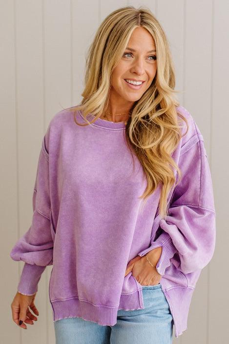 Woman wearing a purple sweatshirt with a neutral background