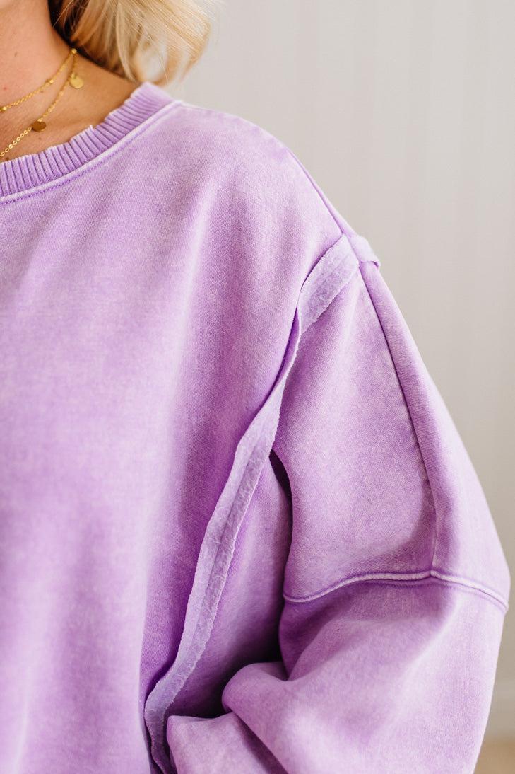 Close-up of a person wearing a purple sweatshirt against a neutral background