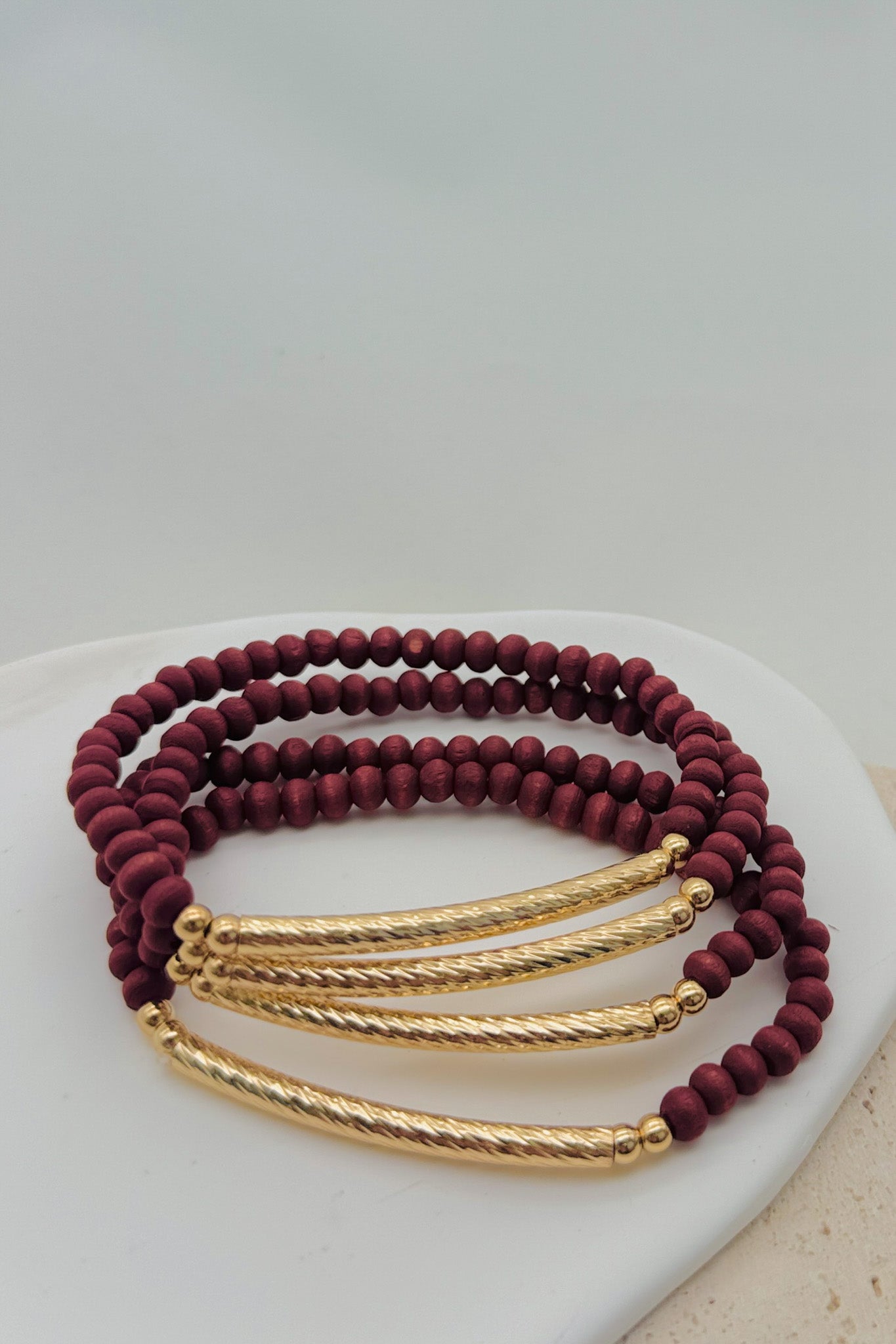 Set of maroon and gold bracelets on a white surface