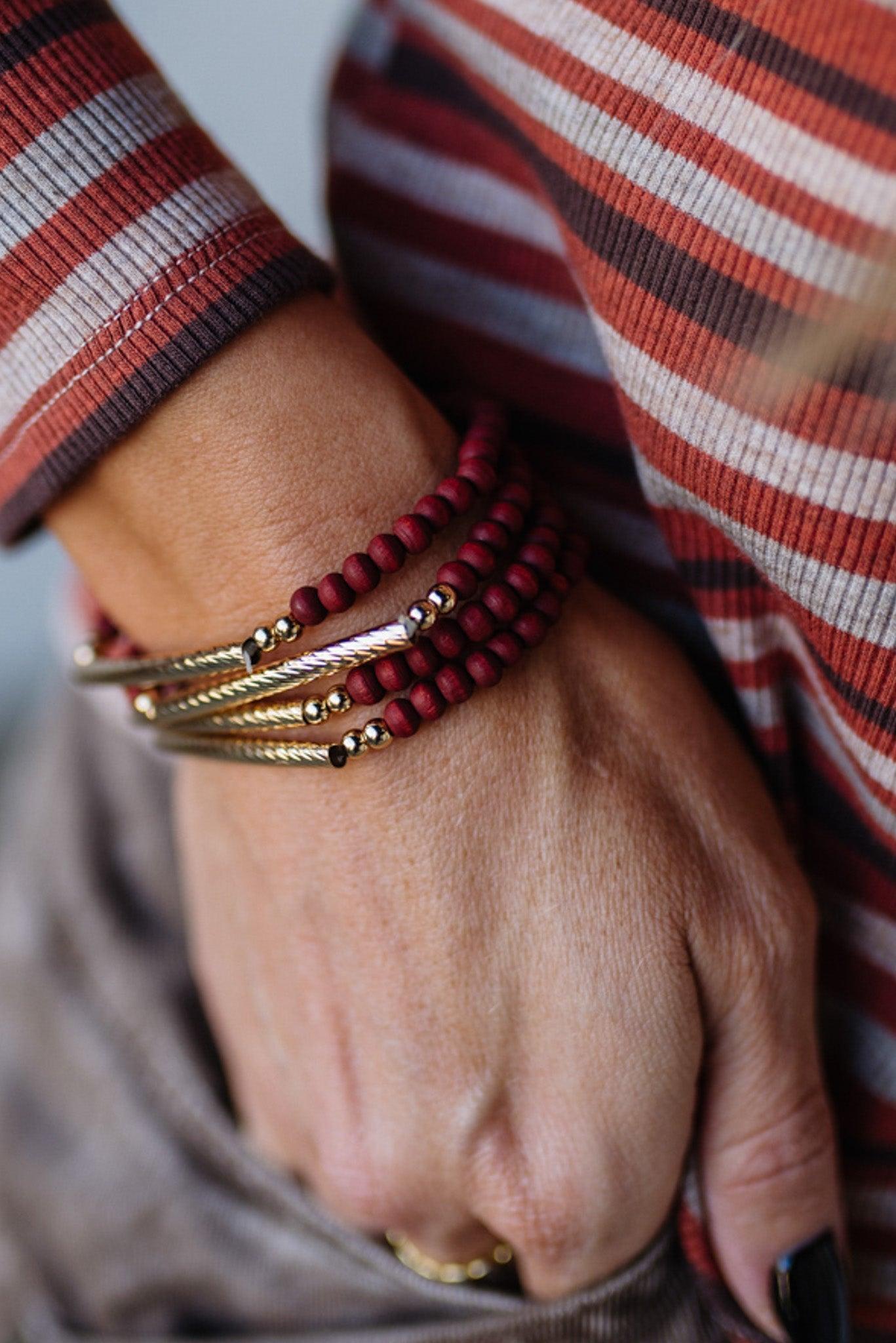 Close-up of a hand wearing multiple bracelets with a striped garment in the background