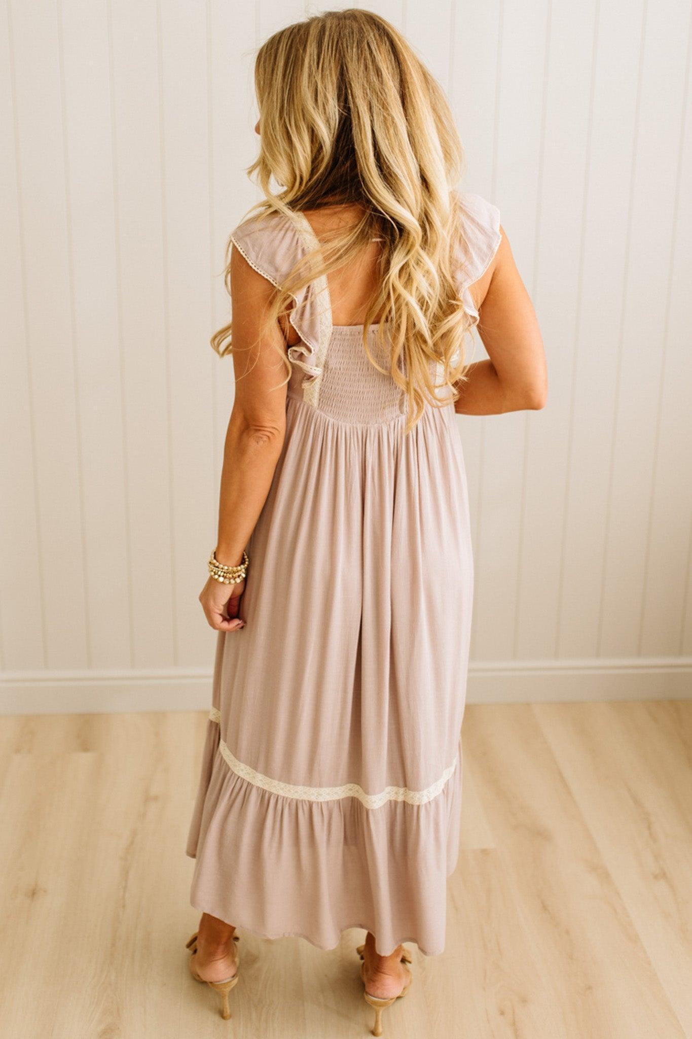 Woman wearing a long, light-colored dress with a white background